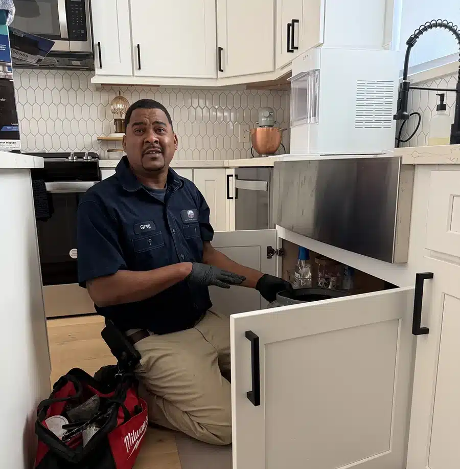 Greg from Luke's working under a Houston kitchen sink